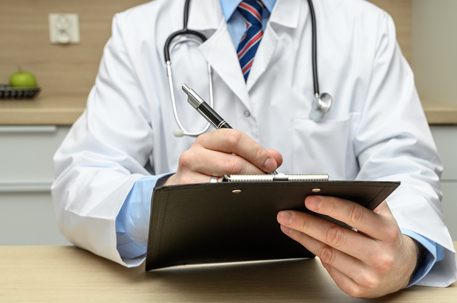 The,Doctor,Sits,At,The,Desk,And,Writes,Something,,Issuing