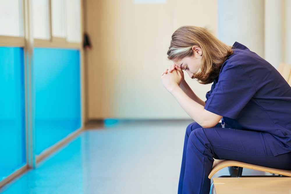 Exhausted,Nurse,Feeling,Stressed,Sitting,In,Hospital,Corridor
